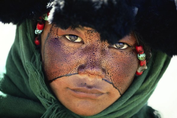 TIBET - Una ragazza nomade con il volto cosparso di una sostanza protettiva durante un pellegrinaggio Tibet, Cina 1990